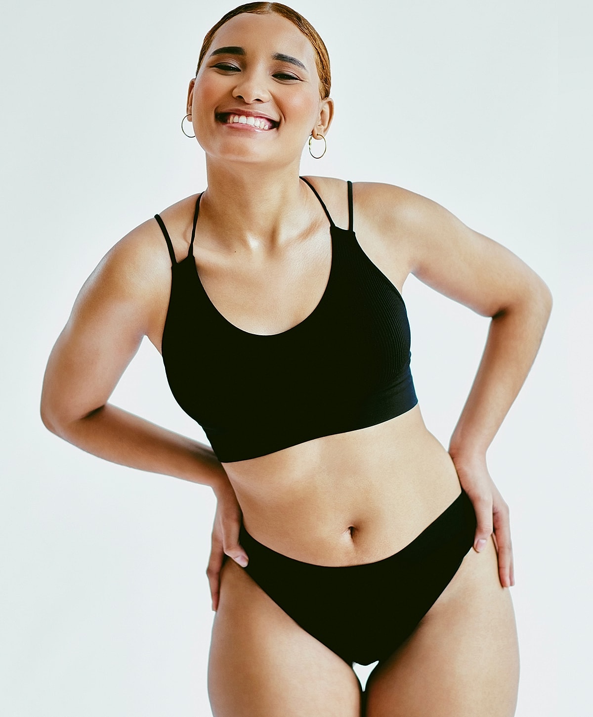 Smiling person in black activewear against white background.