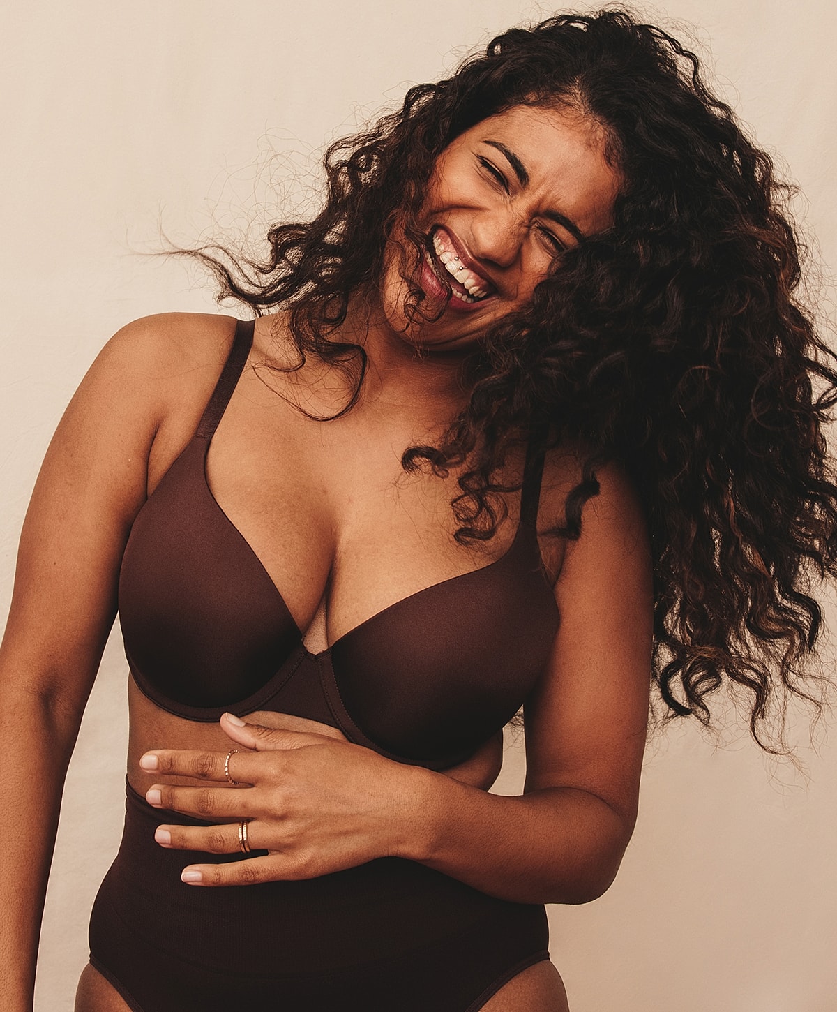 Smiling woman in brown bra and shapewear.