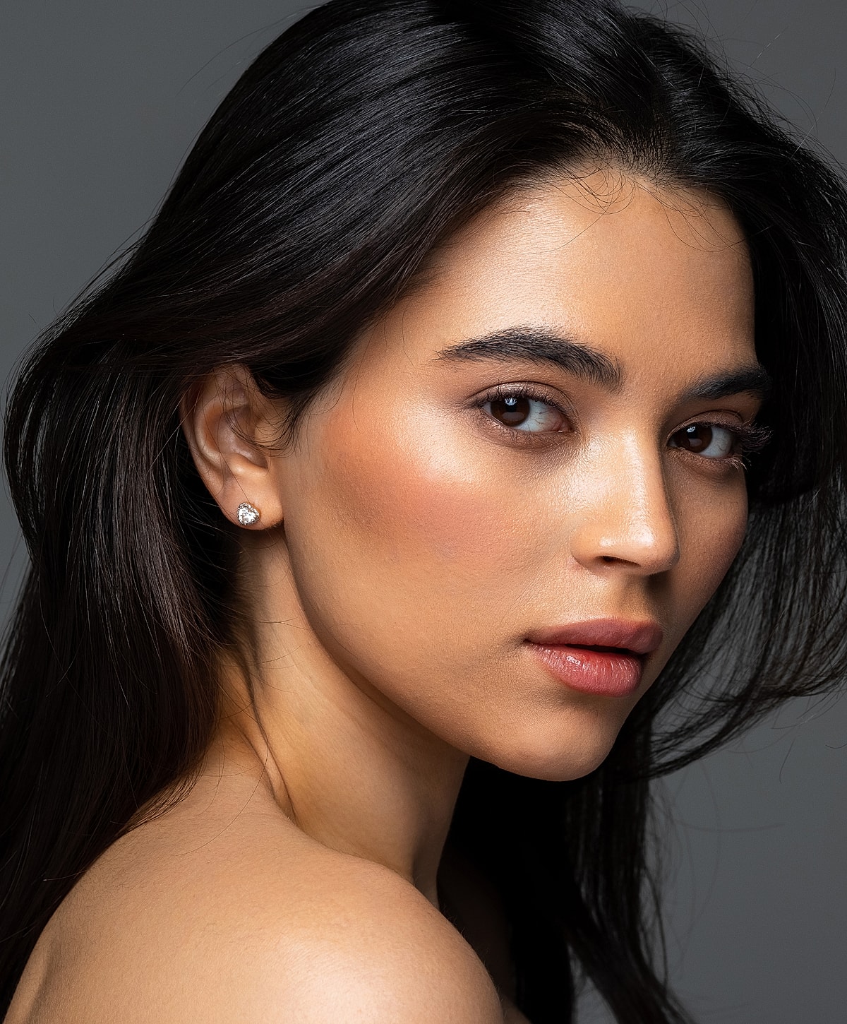 Young woman with long hair and earrings.