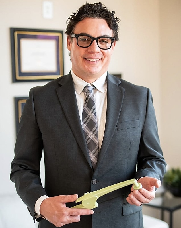 Man in suit holding a green tool.