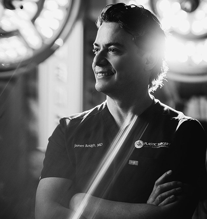 Smiling plastic surgeon in a clinical setting.