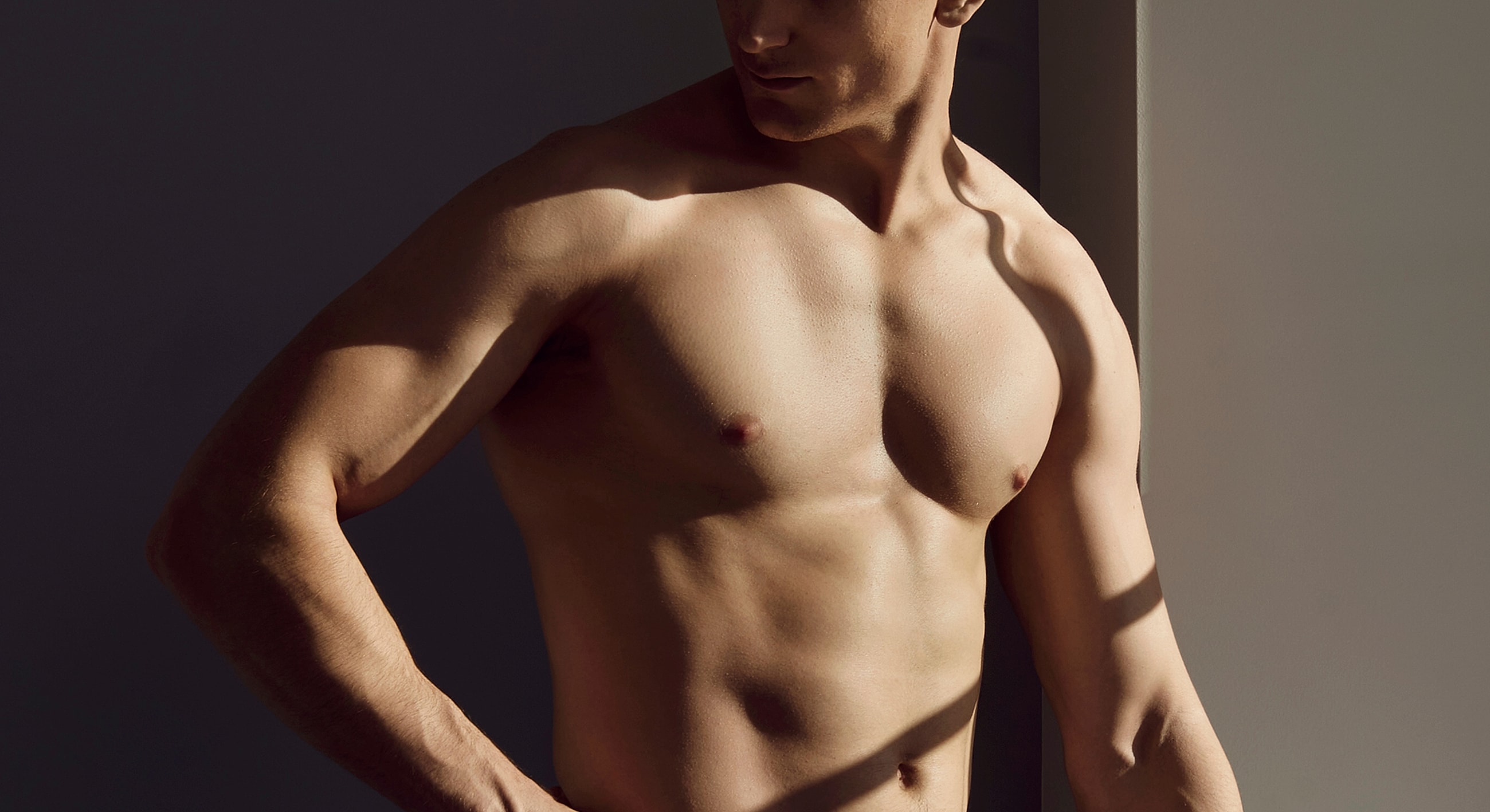 Male model posing in soft lighting and shadows.